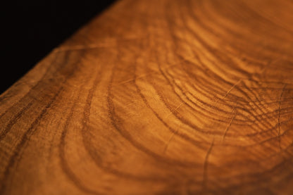 Fine growth rings and subtle hairline surface checking spread across a polished, climate-stable timber section.  