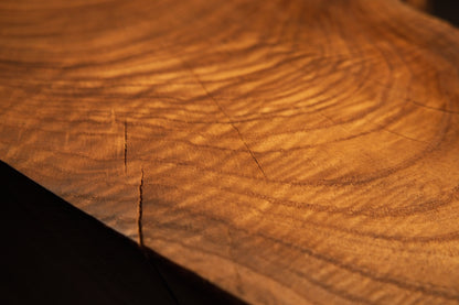 Warm amber growth rings and delicate radial hairline checking mark the face of a solid structural hardwood block.  