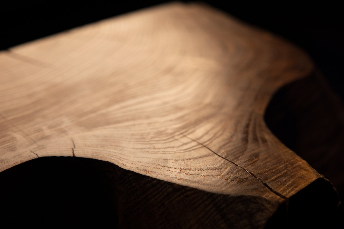 Macro photography angle across a smooth polished wooden surface revealing fine linear grain patterns and subtle checking. 