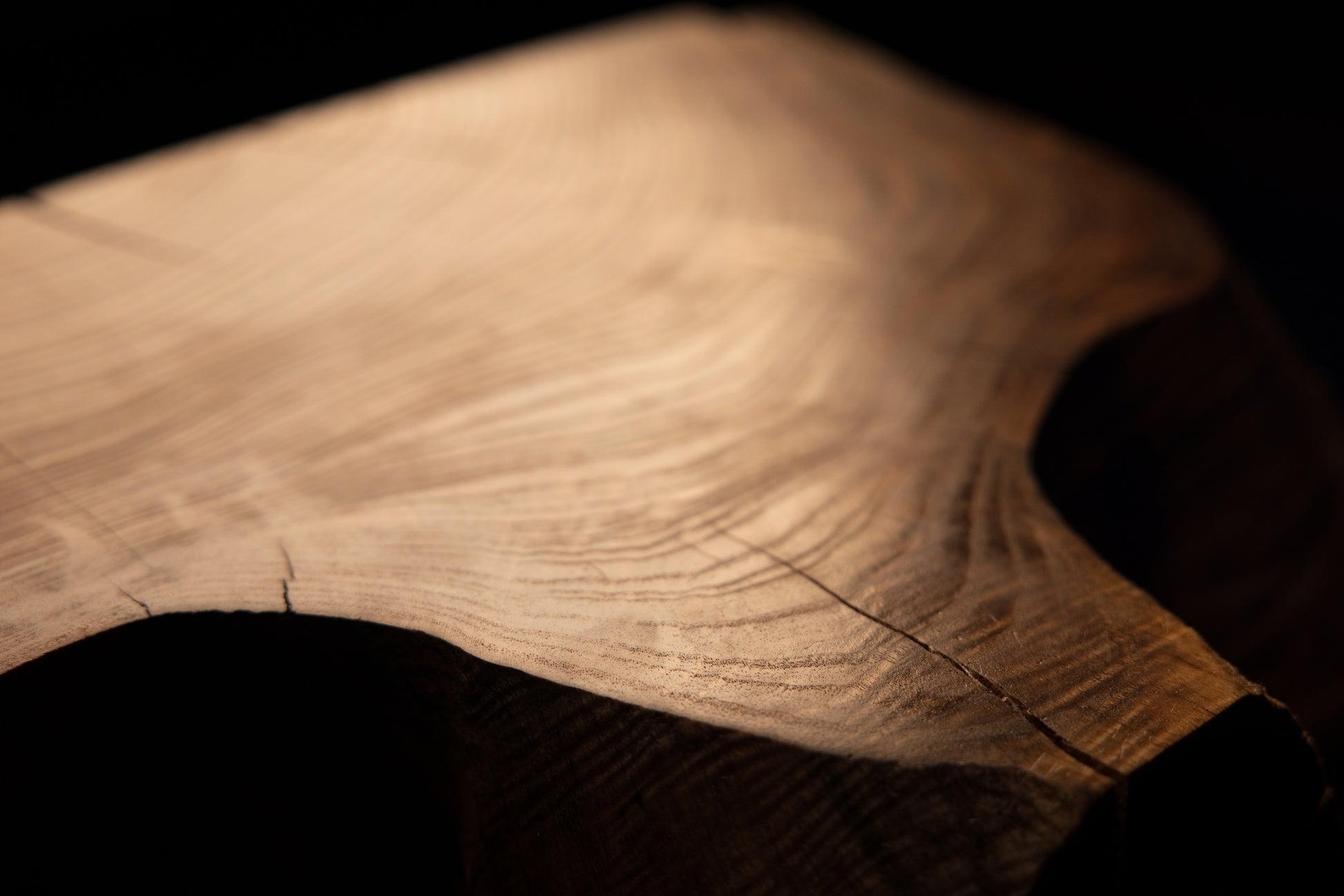 Macro photography angle across a smooth polished wooden surface revealing fine linear grain patterns and subtle checking. 
