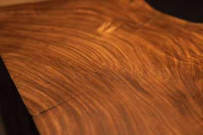 High-magnification capture of shimmering chatoyant light reflections and complex swirling grain across the wooden plane. 