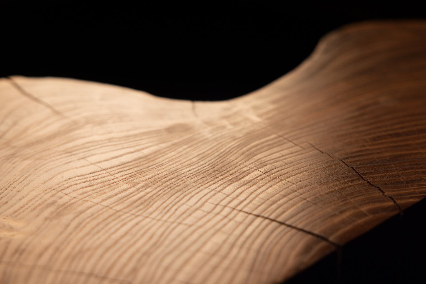 Close-up framing of a gently undulating wooden surface demonstrating seamless grain continuity and warm amber coloration. 