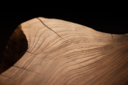 Diagonal macro angle catching a fine linear fracture line slicing across rich golden wood grain patterns on the slab. 