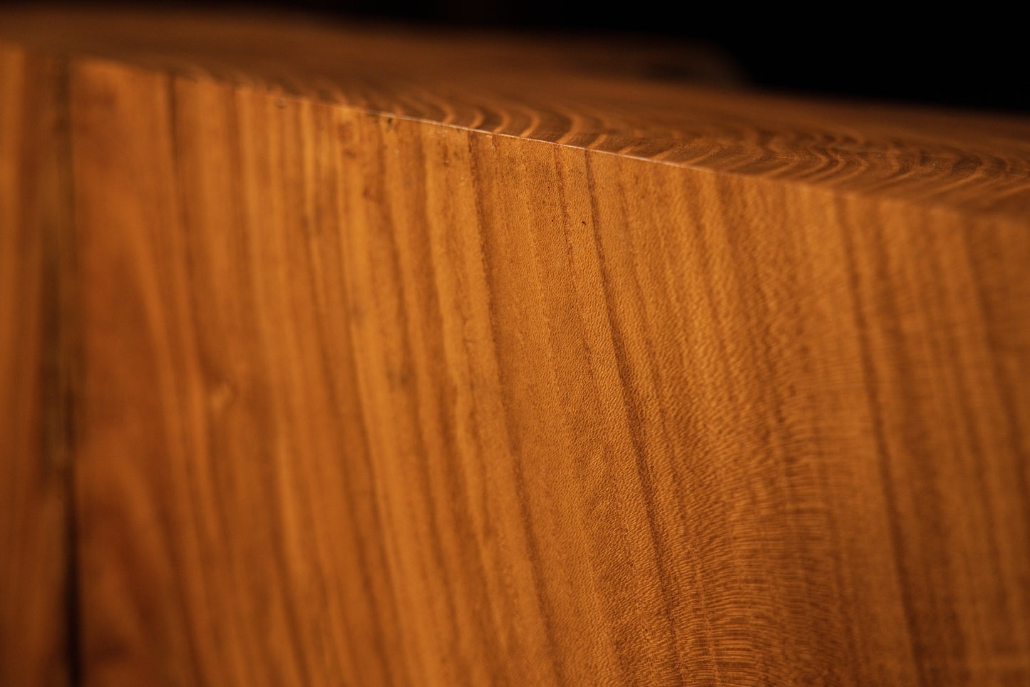 Sharp close-up perspective framing an upper corner on a solid structural wooden block with clean vertical grain alignment. 