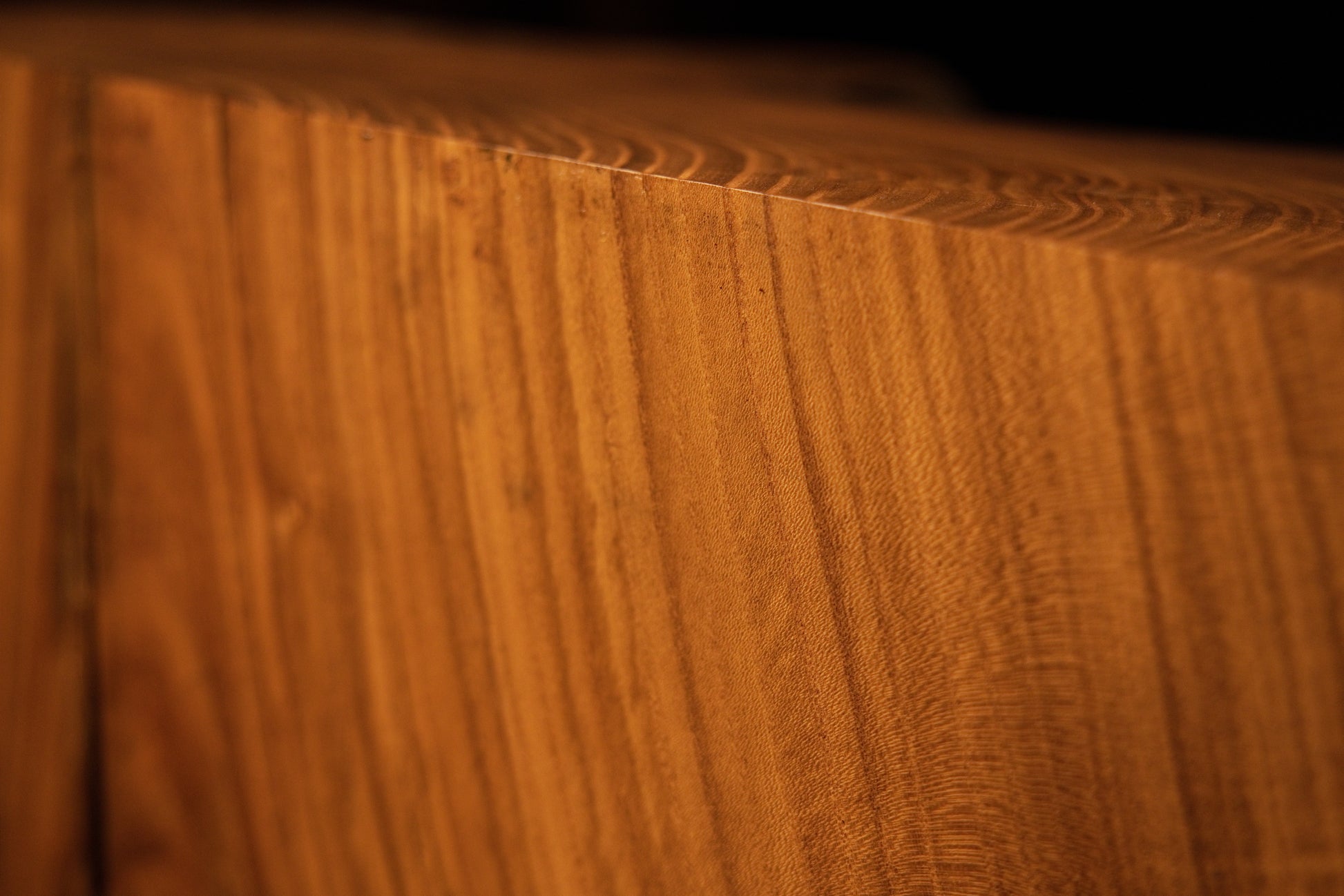 Sharp close-up perspective framing an upper corner on a solid structural wooden block with clean vertical grain alignment. 
