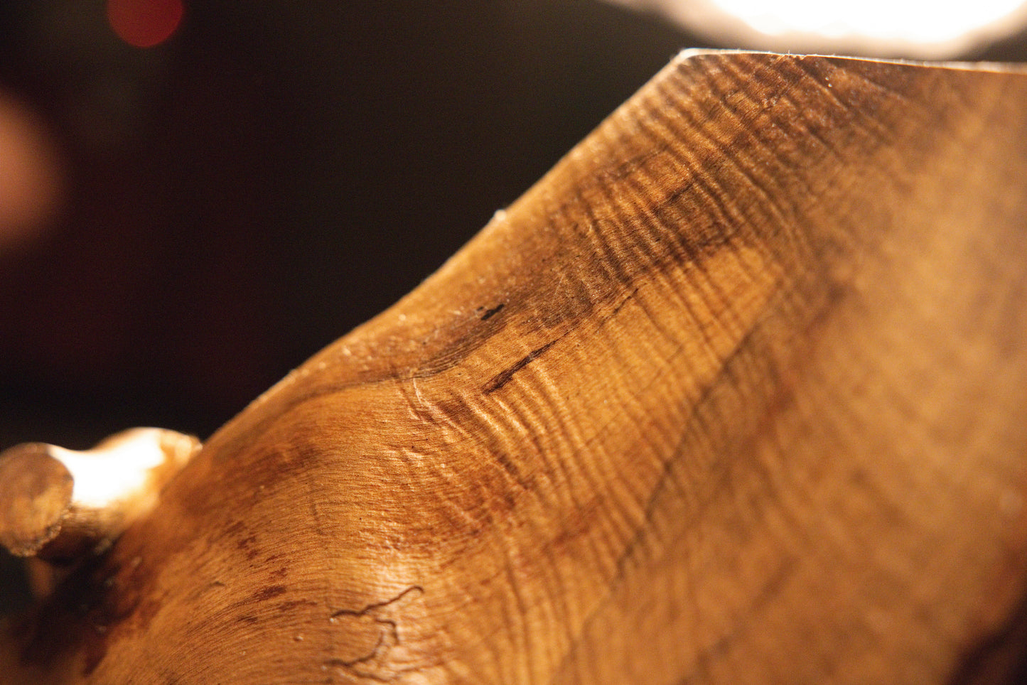 Gallery close-up photograph showcasing fine linear wood texture and rich warm color variations across the sculpture face. 