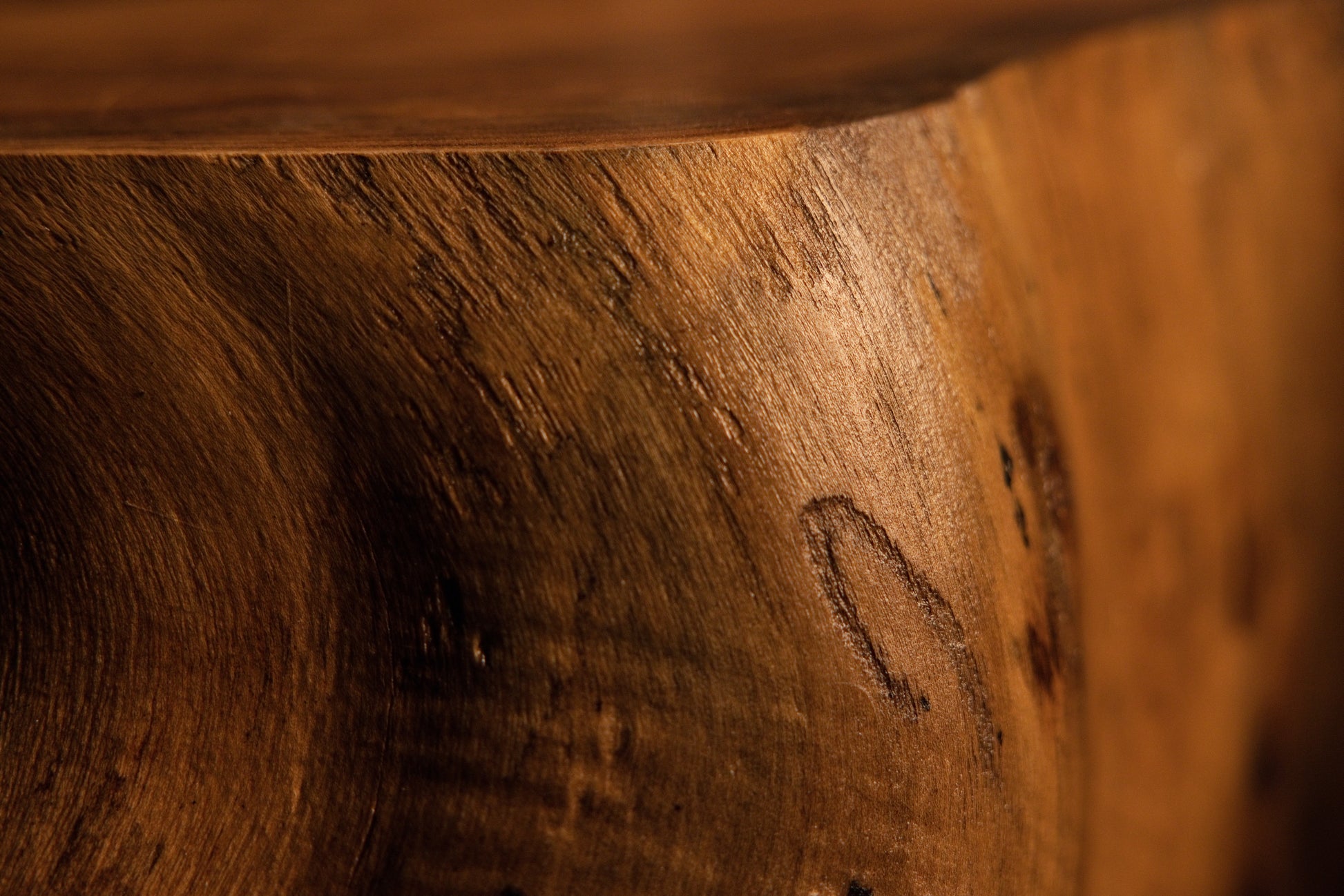 Close-up perspective of a polished wooden block edge exhibiting clean grain patterns and a subtle natural indent mark. 