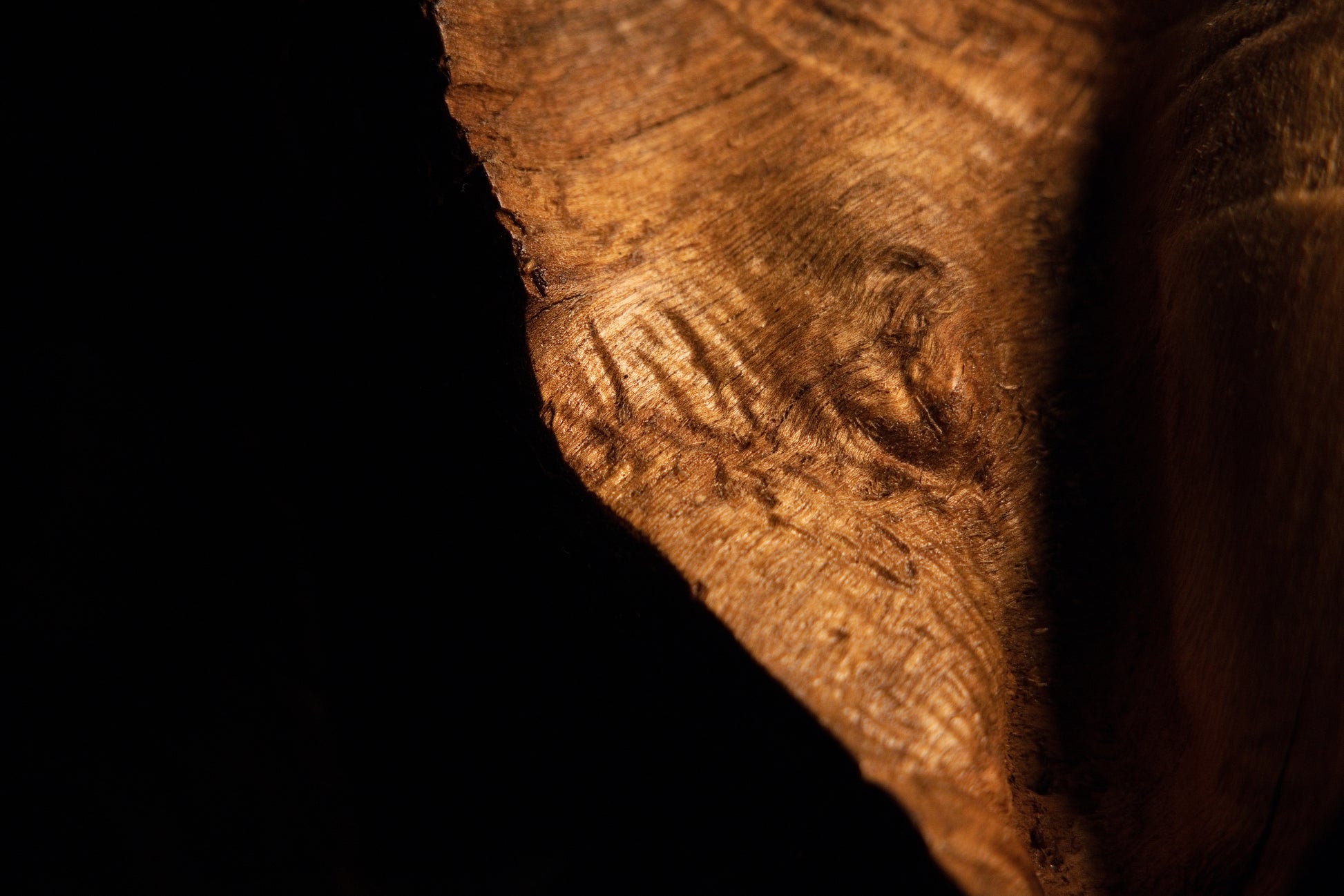 Perspective close-up of a polished wooden edge showing tight natural grain contours and an embedded dark knot detail. 
