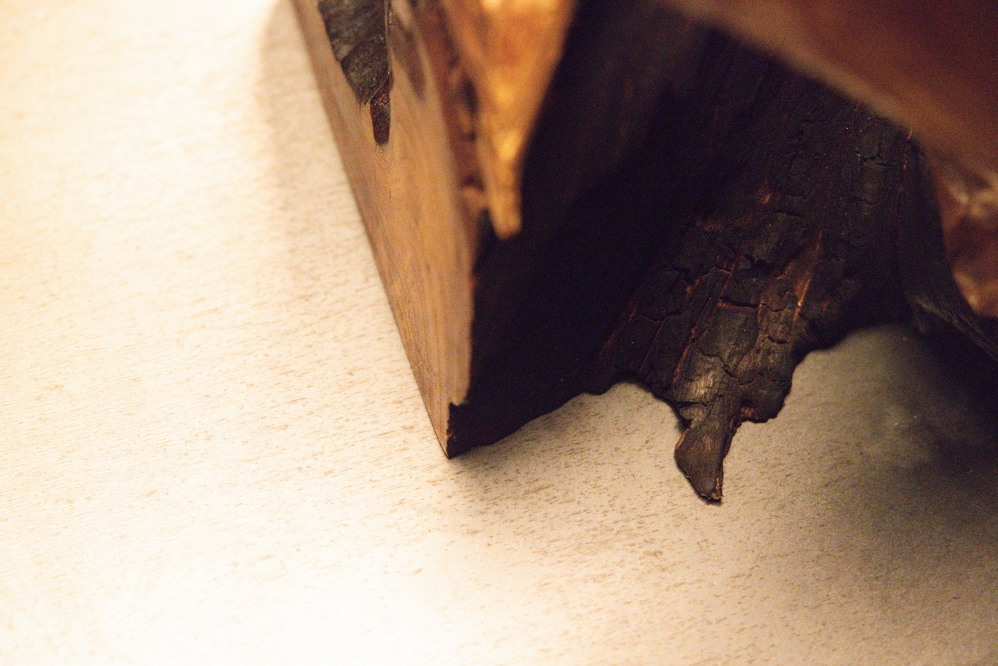 Macro photograph showing a natural solid wood surface converging towards a deep dark vertical fissure in the block. 