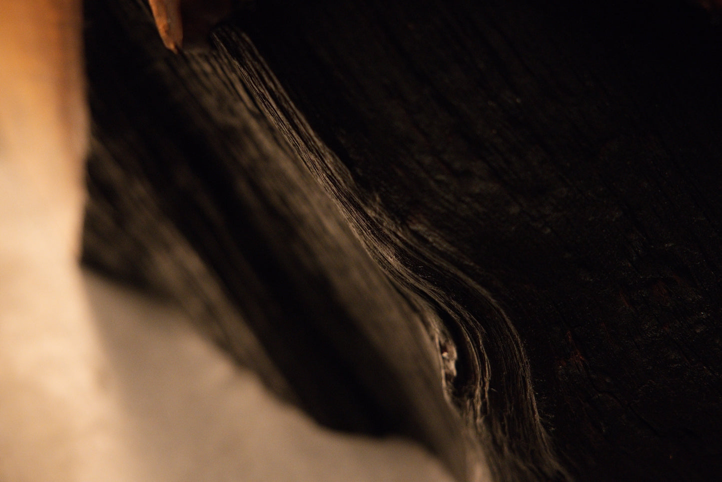 Close-up perspective of a polished wooden block edge showcasing tight natural grain contours and an embedded knot. 