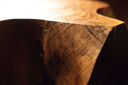 Close-up macro perspective showcasing fine linear wood textures and warm golden light playing across the heavy block. 