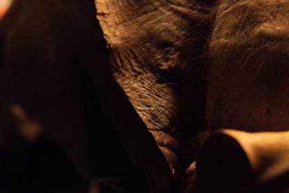 Detailed macro photograph capturing a polished solid wooden block corner casting dramatic shadows across the art piece. 