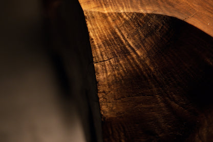 Detailed macro view capturing a dark weathered timber surface merging into deep recessed structural shadows on art. 