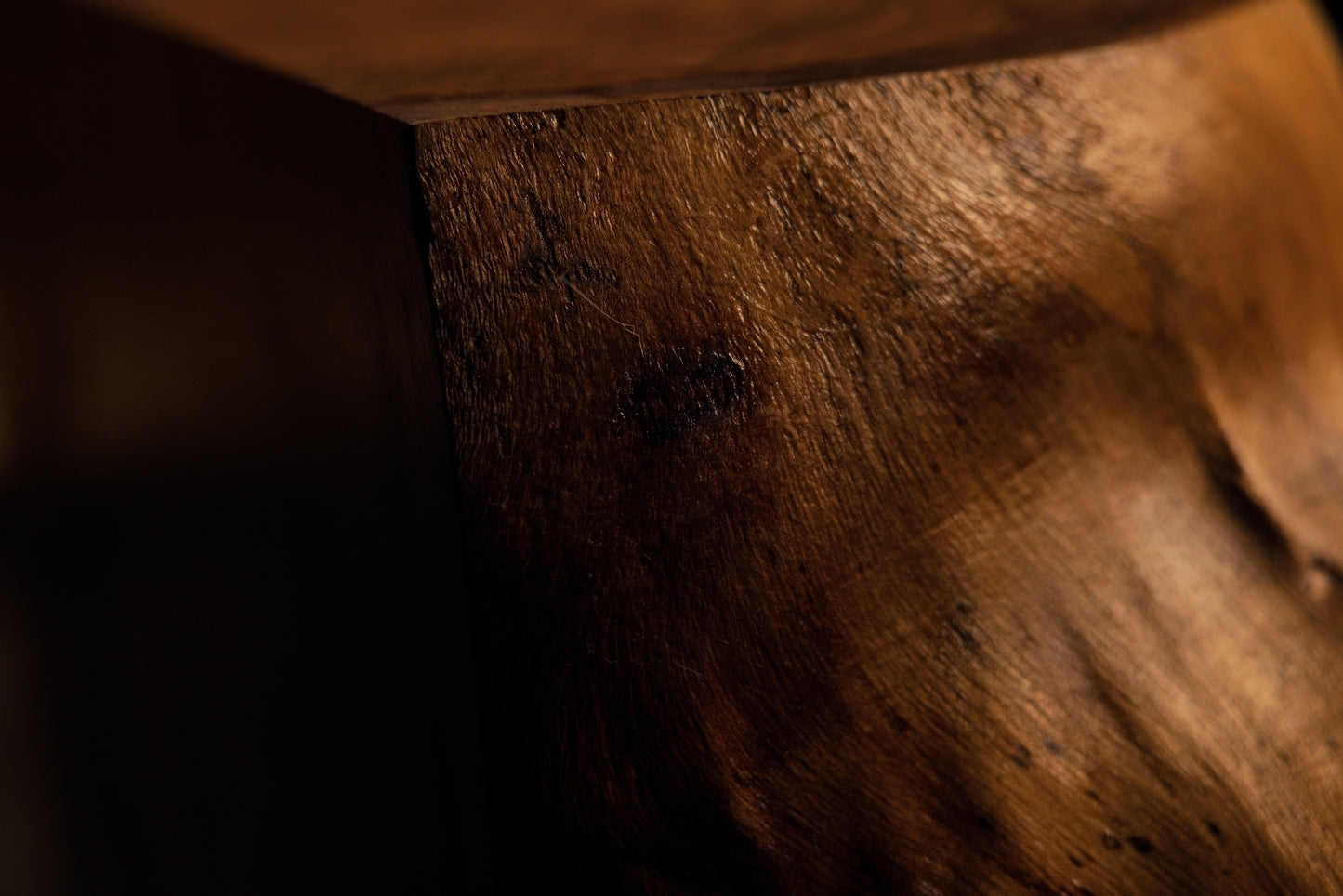 Detailed close-up macro of a solid structural wooden block face showing rich grain textures and natural lighting. 